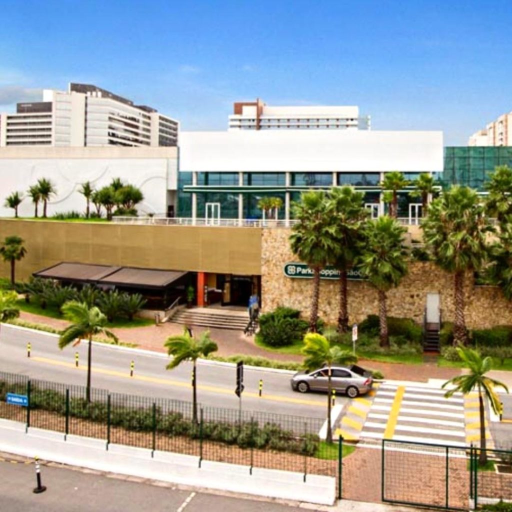 O Park Shopping São Caetano, capturado sob o céu azul, exibe uma fachada moderna com vegetação tropical, uma visão acolhedora que convida visitantes a um destino de compras e lazer na cidade